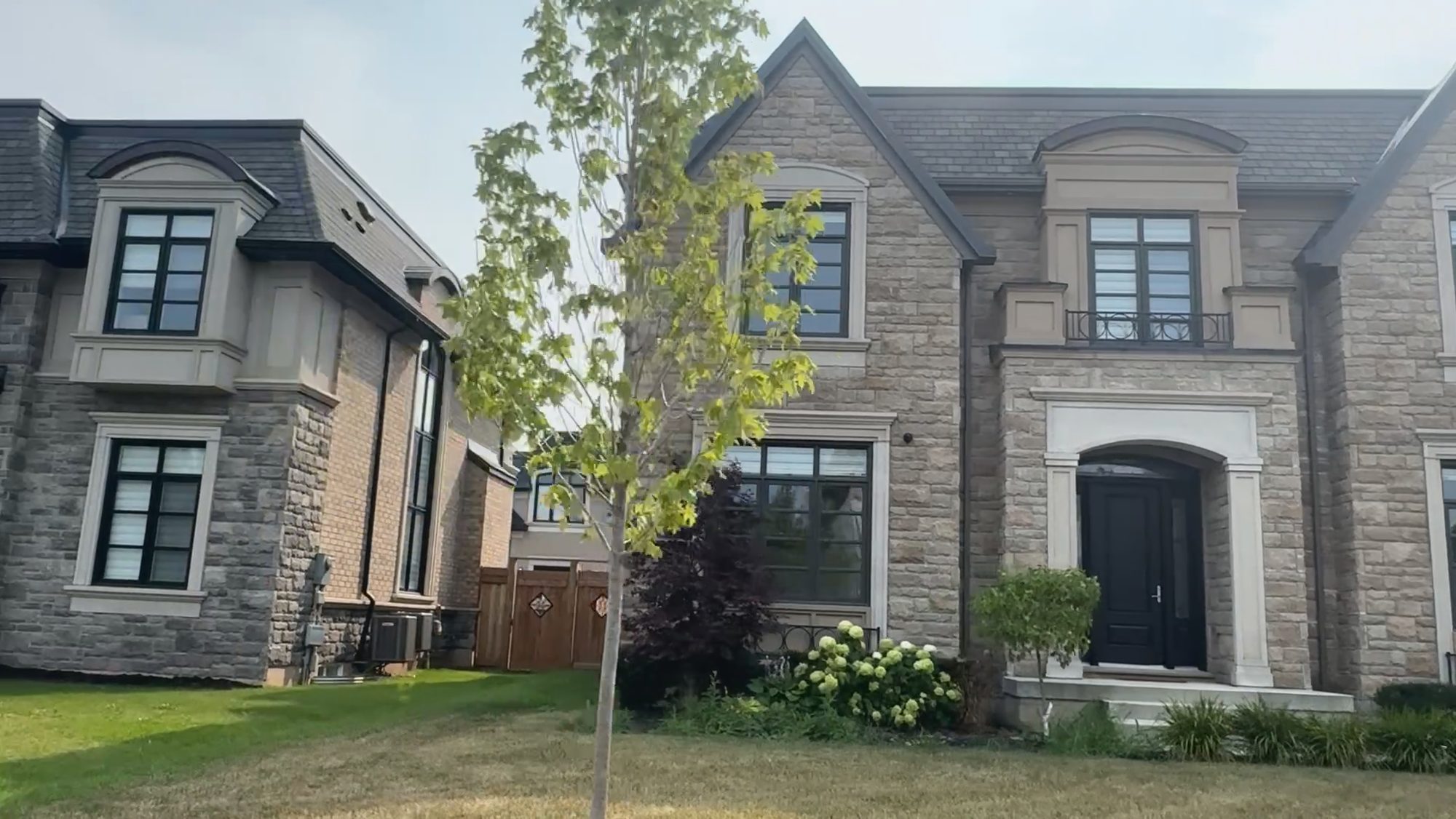 A large new stone-fronted house on a young, newly landscaped lot