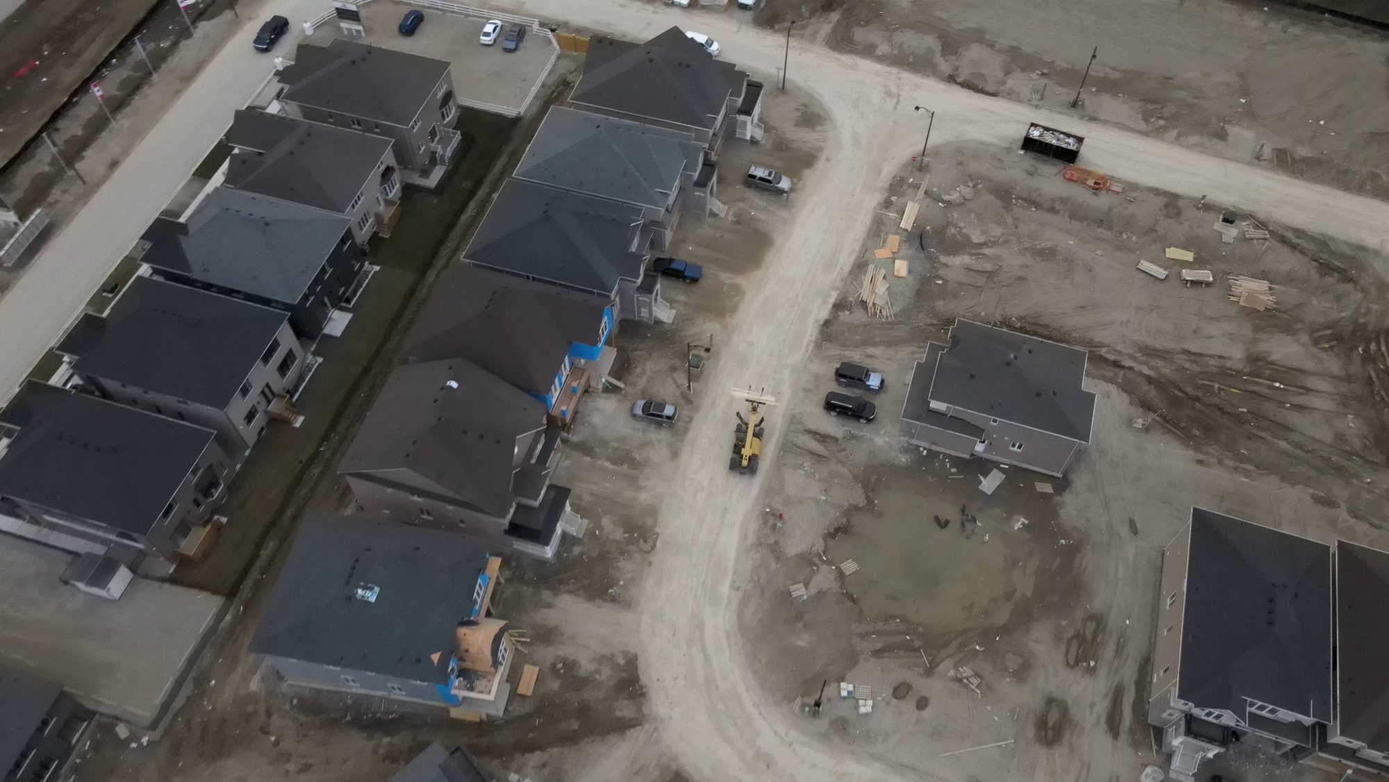 New houses going up along a road still under construction, seen from the air
