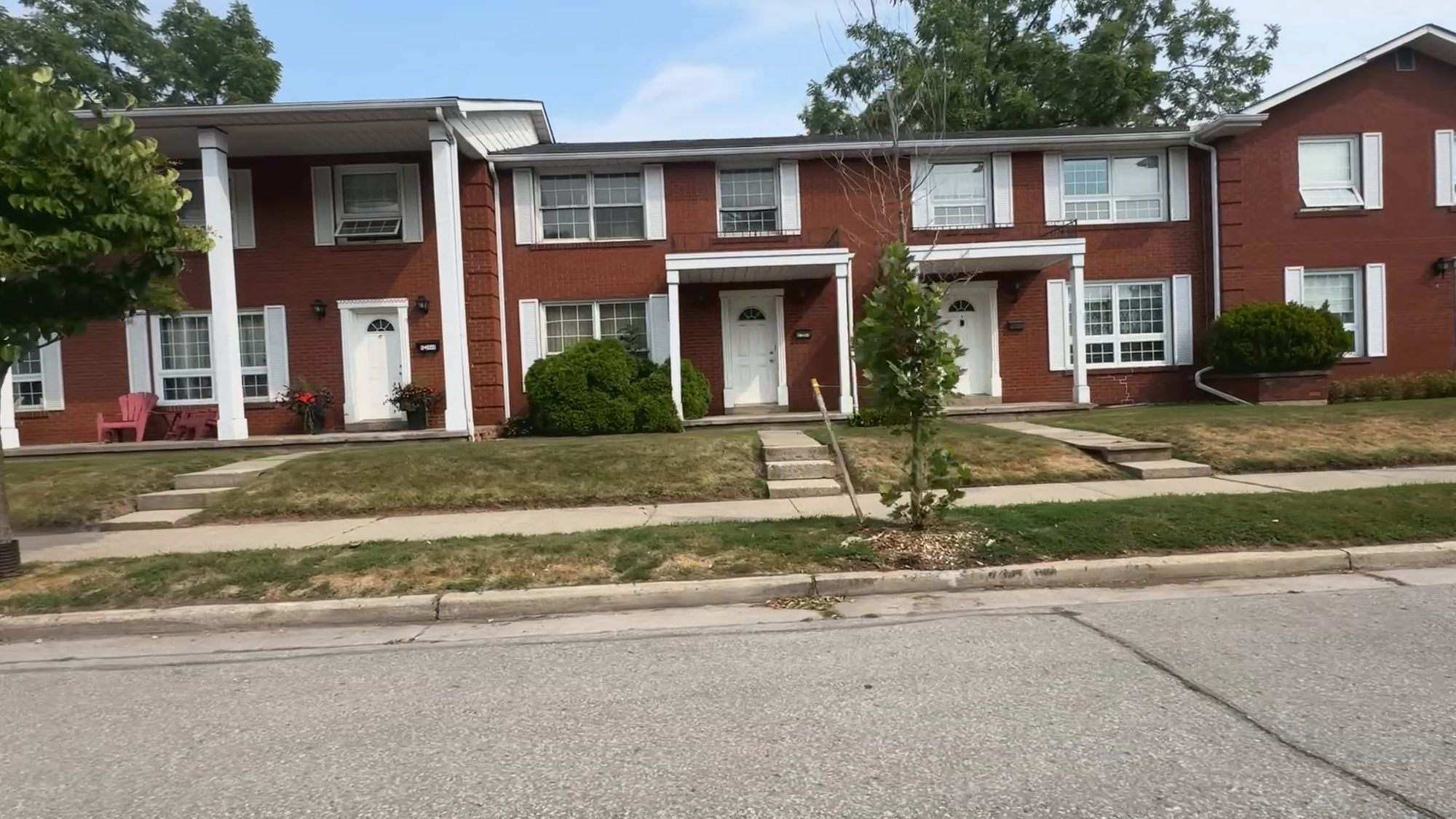 A row of two-storey red brick townhouses behind a strip of lawn