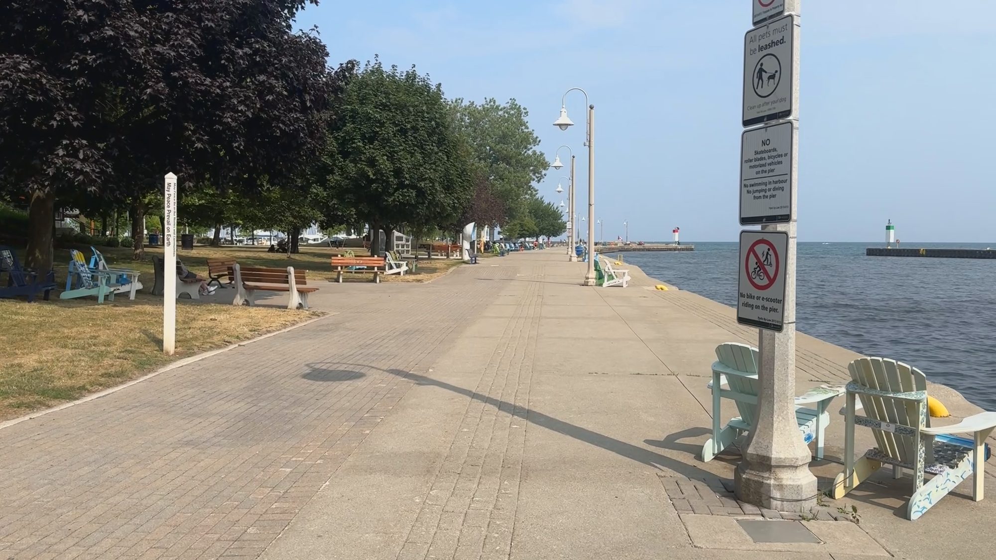 A lakefront walkway with benches running out toward a pier light