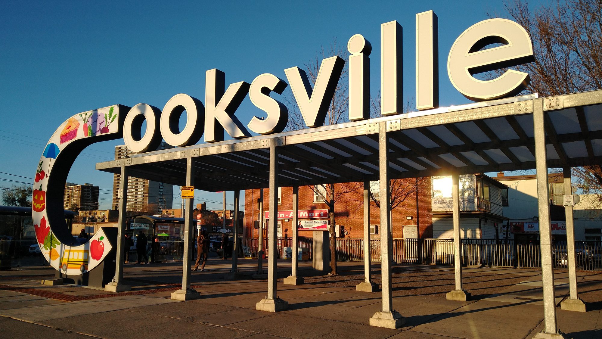 The illustrated Cooksville sign standing over the transit shelter at the Four Corners